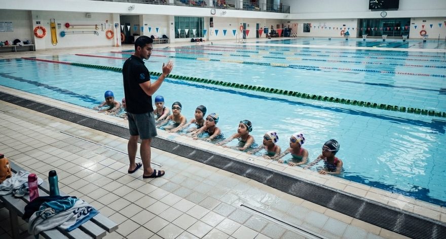 Star Swim squad lined up at the pool edge as their coach briefs them at a competition-size pool